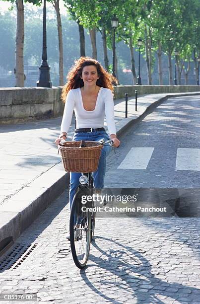 young woman riding bicycle along cobbled street - paris street woman stockfoto's en -beelden