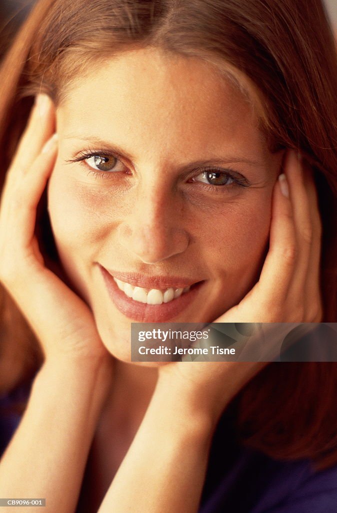 Young woman with hands on face, smiling, close-up, portrait