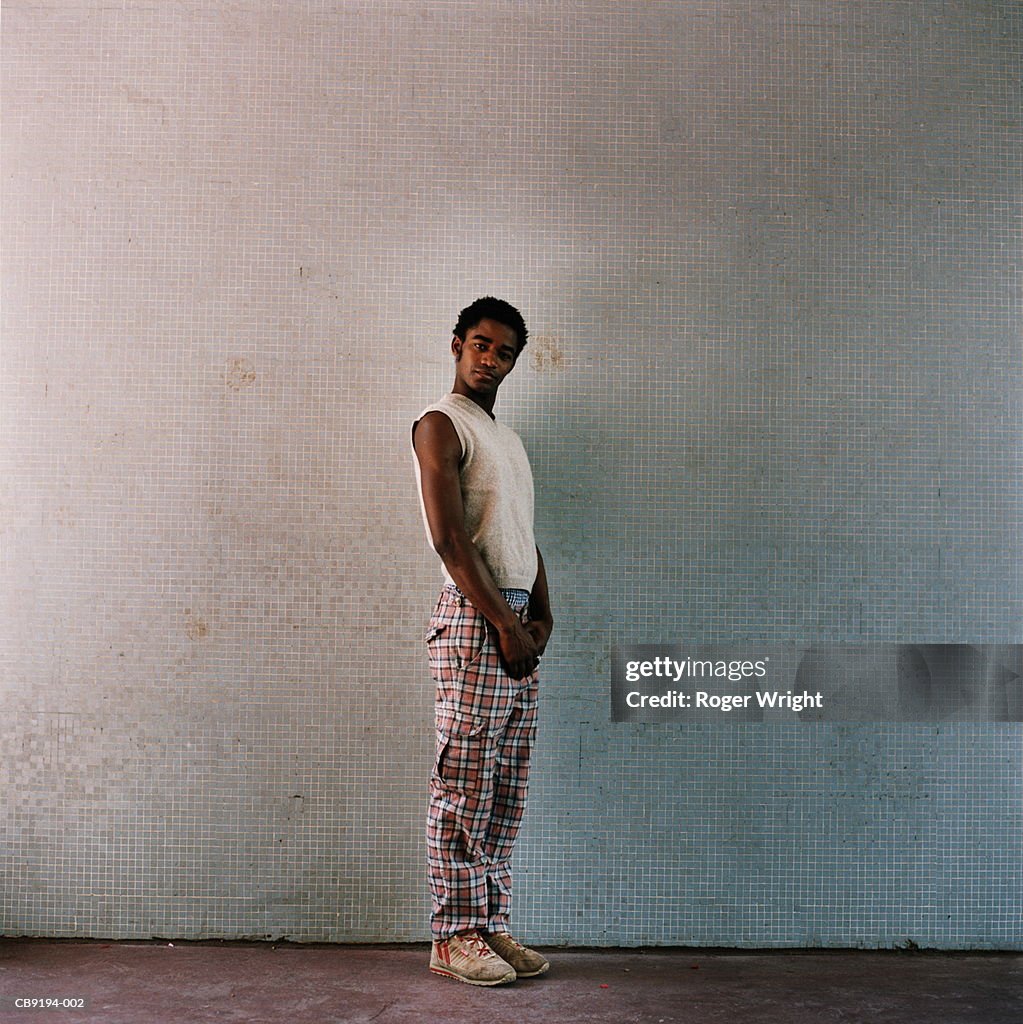 Young man standing in front of tiled wall, portrait