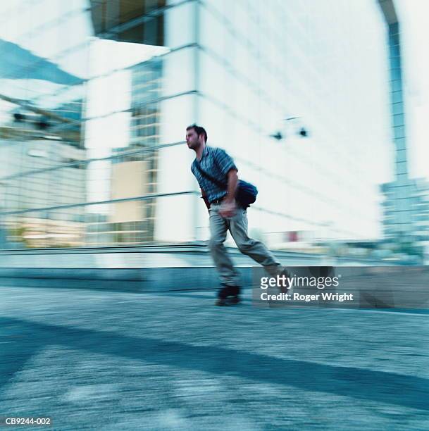 young man in-line skating, in front of office block (blurred motion) - city block ストックフォトと画像