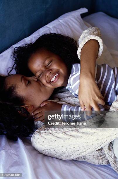 mother and daughter (4-6) embracing, elevated view - man and woman kissing in bed stock-fotos und bilder