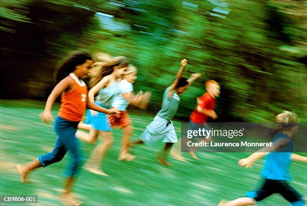 group of children (8-11) running across grass (blurred motion) - fangspiel stock-fotos und bilder