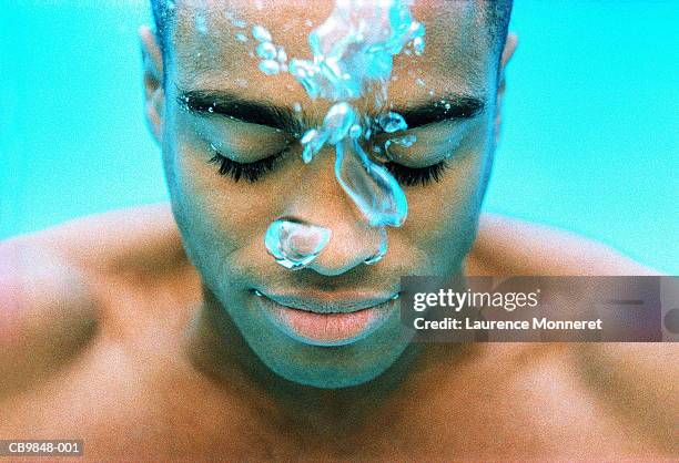 young man breathing out through nose, underwater view - aquatic stock-fotos und bilder