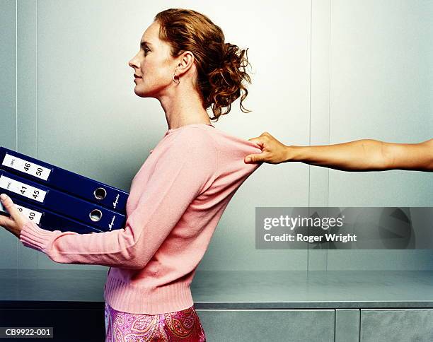 woman carrying folders, hand grabbing woman's jumper, profile - held back stock pictures, royalty-free photos & images