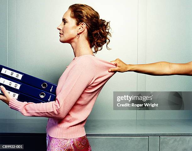 woman carrying folders, hand grabbing woman's jumper, profile - side view carrying stock pictures, royalty-free photos & images