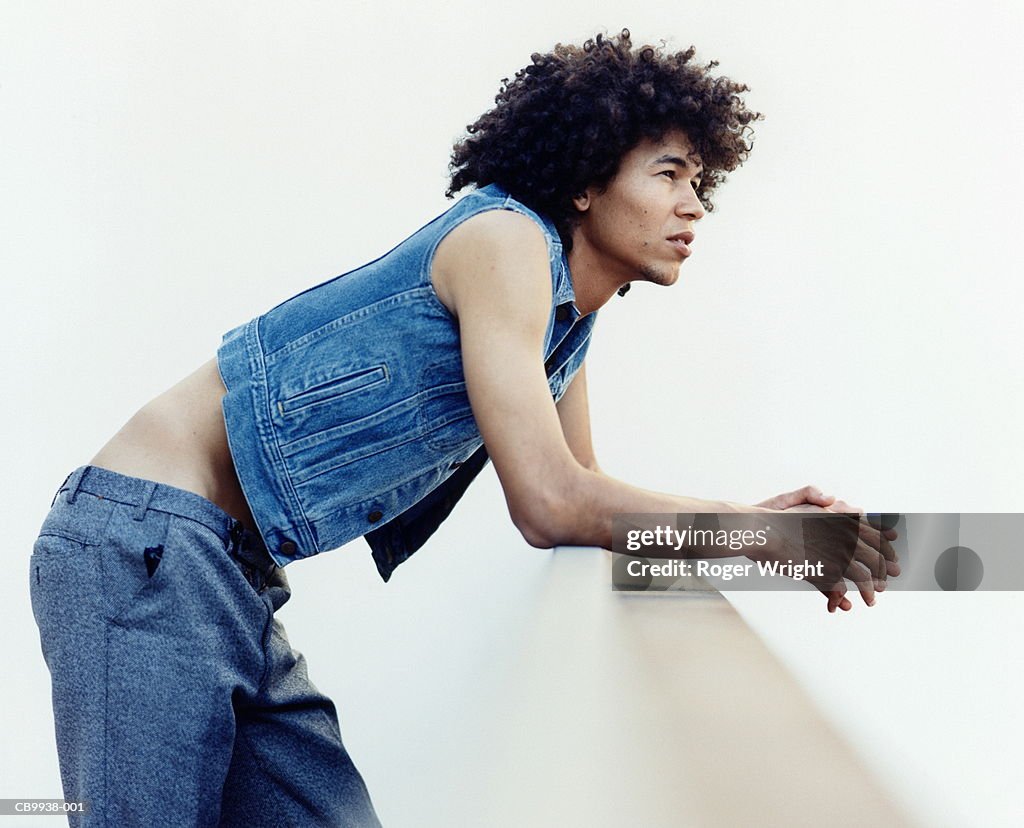 Young man leaning on wall, profile