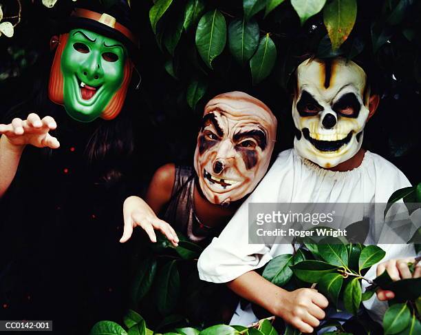 three children wearing halloween masks - child mask stock pictures, royalty-free photos & images