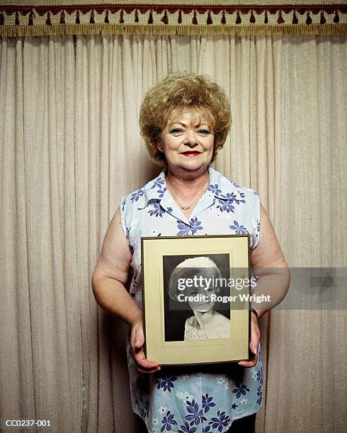 mature woman holding photograph of younger self, portrait - self portrait photography 個照片及圖片檔