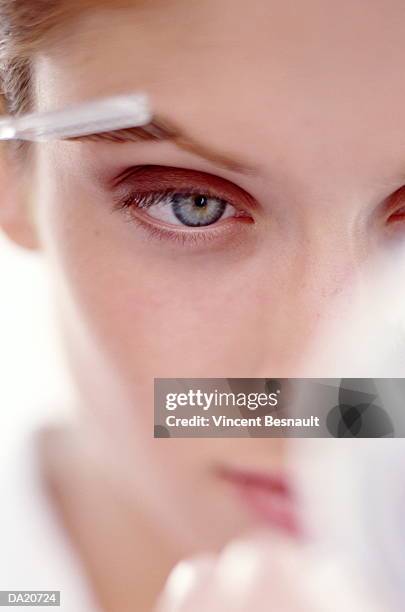 young woman applying make-up to eyebrow, close-up - close up woman eyes stock-fotos und bilder