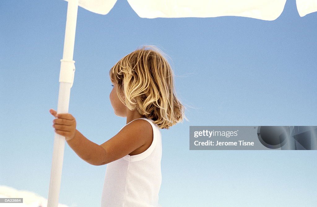 Girl (3-5) standing under umbrella, high section, rear view