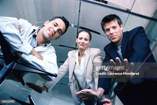 three business people leaning on glass table, low angle view - 3 men looking up stock pictures, royalty-free photos & images