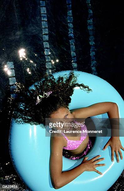 girl (8-10) floaring in rubber ring in pool, overhead view - rubber ring stock-fotos und bilder
