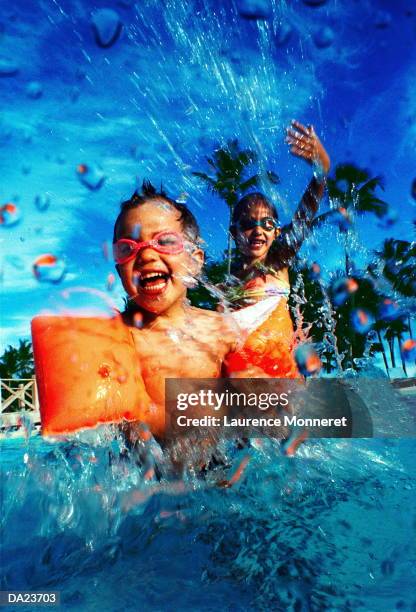 two children playing in swimming pool (grainy) - swimming pool jump stock pictures, royalty-free photos & images