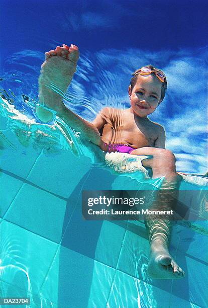 boy (8-10) dangling feet in swimming pool, low angle view - kid under water stock-fotos und bilder