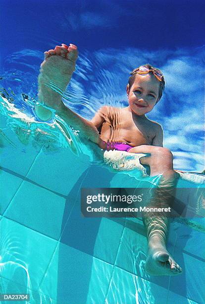 boy (8-10) dangling feet in swimming pool, low angle view - boy 10 11 stock pictures, royalty-free photos & images