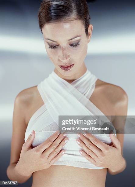 naked young woman with bandages on torso, cupping breasts - pechos mujer fotografías e imágenes de stock