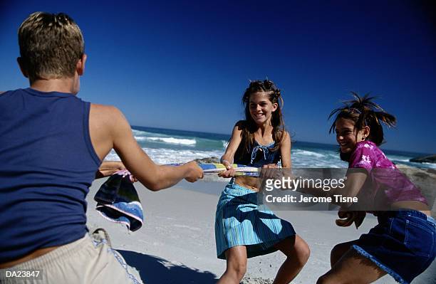 group of teenagers (11-13) playing tog-of-war on beach, summer - war stock-fotos und bilder