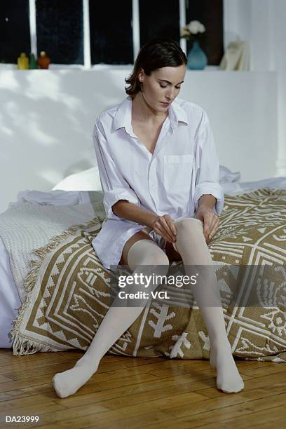young woman putting on stockings - women wearing nylons photos et images de collection