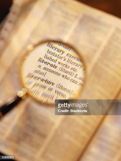 magnifying glass enlarging words from dictionary - analfabetism bildbanksfoton och bilder