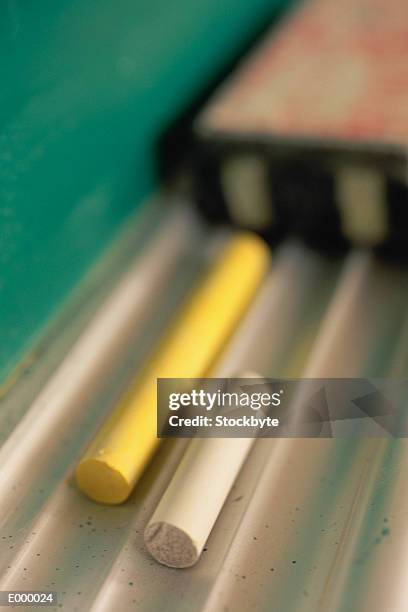 chalk resting on chalkboard tray, eraser in background - chalkboard eraser stockfoto's en -beelden