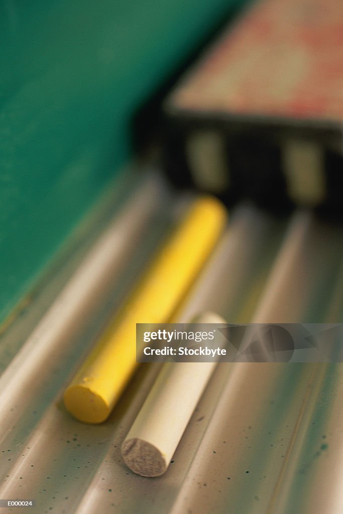 Chalk resting on chalkboard tray, eraser in background