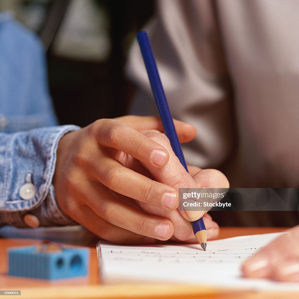 Child's hand guiding adult's hand through writing exercise