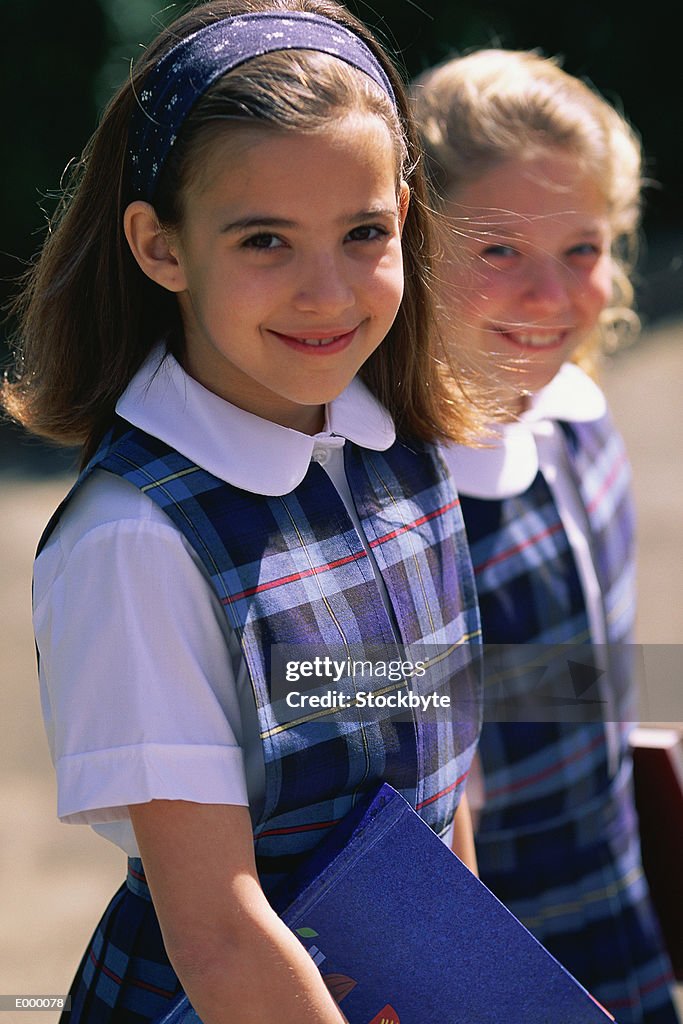 Two girls in school uniforms, smiling and posing