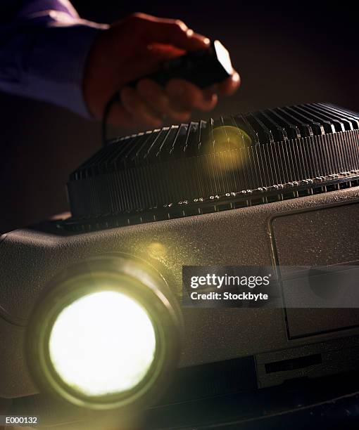 slide projector; hand holding remote control in background - slide projector stock pictures, royalty-free photos & images