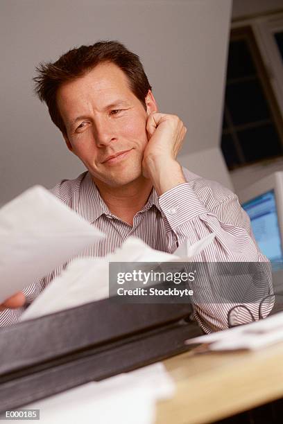 man looking at papers, resting head on hand - hand on head foto e immagini stock