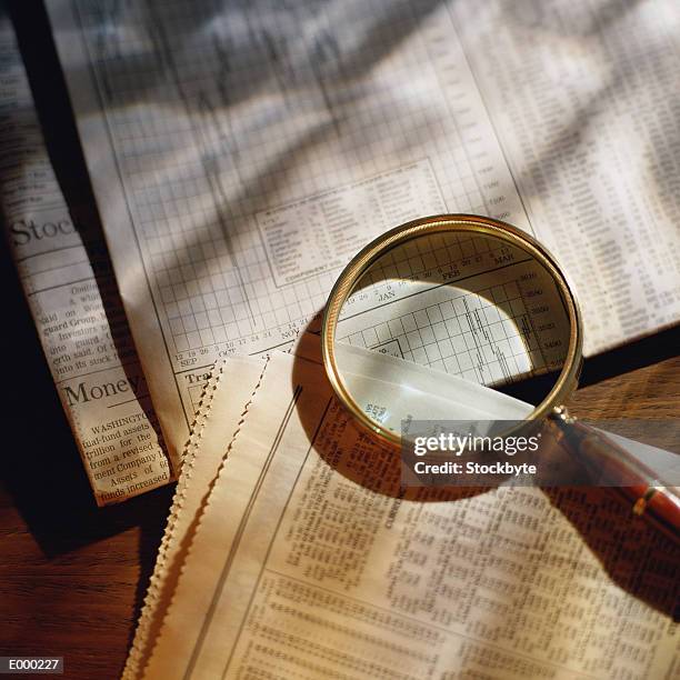 magnifying glass on top of newspaper stock reports - broadsheet stock pictures, royalty-free photos & images