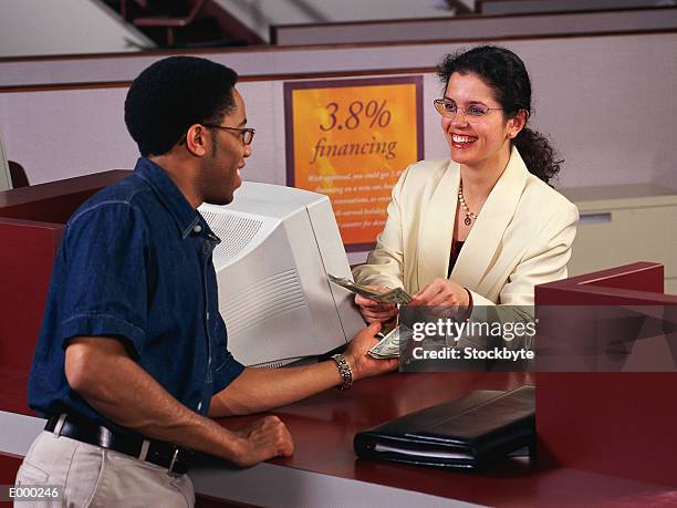 bank teller counting cash into customer's hand, both smiling - bank teller and customer stock-fotos und bilder