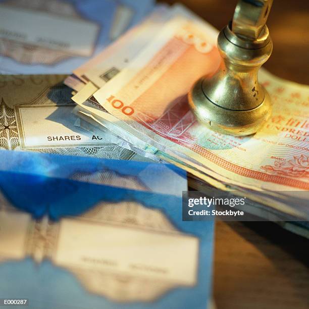 brass seal on top of stack of international currency - paperweight stock pictures, royalty-free photos & images