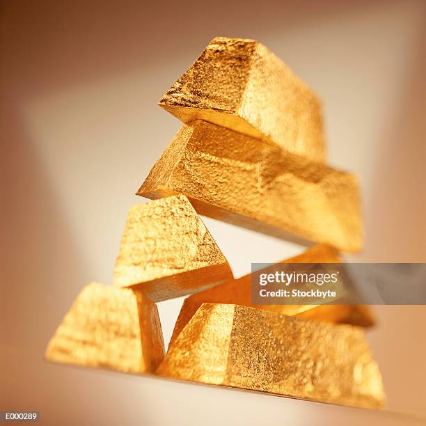 stack of gold bars beginning to topple - devaluation stock pictures, royalty-free photos & images