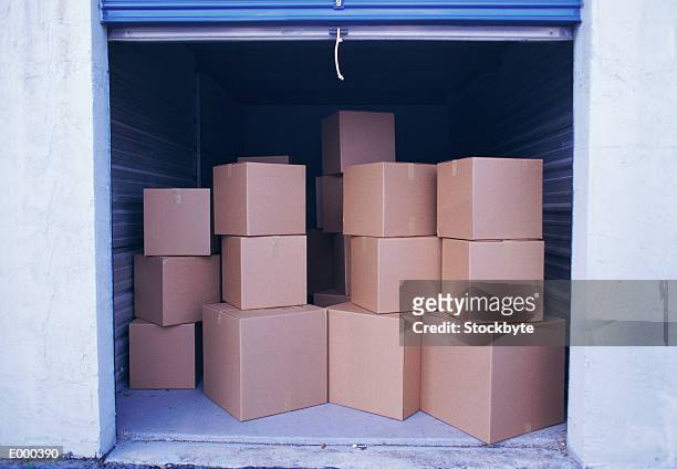 stacks of boxes in open garage - industrial doors stock pictures, royalty-free photos & images