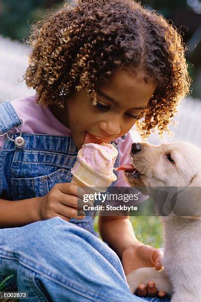 girl sharing strawberry ice cream cone with puppy - girl eating messy ice cream cone stock-fotos und bilder
