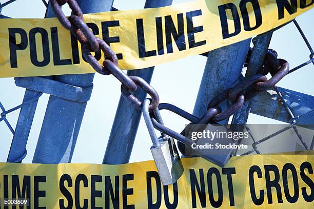 closeup of chain locked gate covered with yellow police tape - restricted area sign stock-fotos und bilder