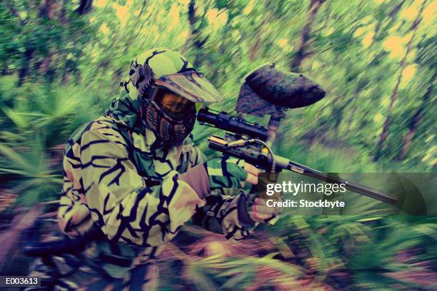 man in fatigues playing paintball, aiming at target in woods - rifle sight stock pictures, royalty-free photos & images