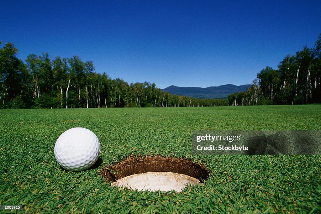 Golf ball next to hole