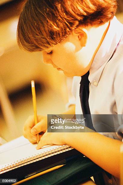 boy writing in spiral notebook - spiral foto e immagini stock