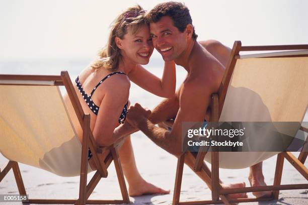 snuggly couple sitting in beach chairs - snuggly stock pictures, royalty-free photos & images