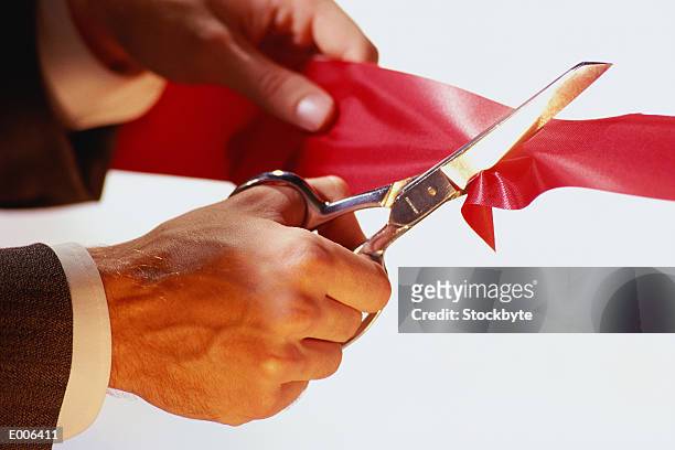 hands cutting red ribbon with scissors - opening celebration of gregory colberts ashes and snow exhibition arrivals stockfoto's en -beelden