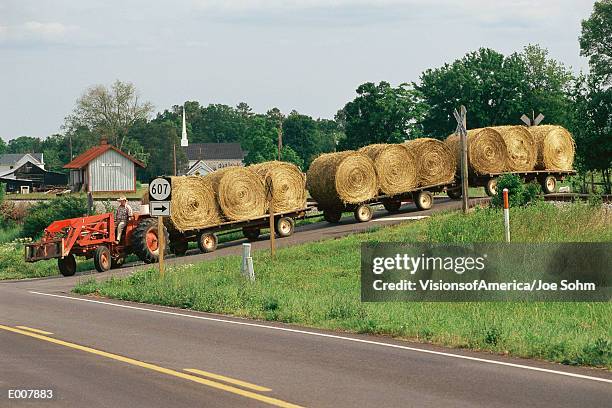 tractor pulling flatbeds with rolled hay bales - hay fotografías e imágenes de stock