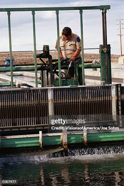 worker cleaning water at fish hatchery - fish hatchery stock pictures, royalty-free photos & images