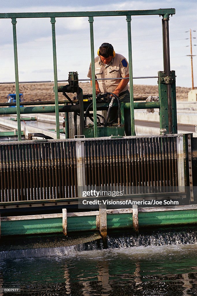 Worker cleaning water at fish hatchery