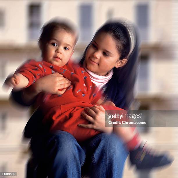 girl holding baby and looking at it fondly - square neckline stockfoto's en -beelden