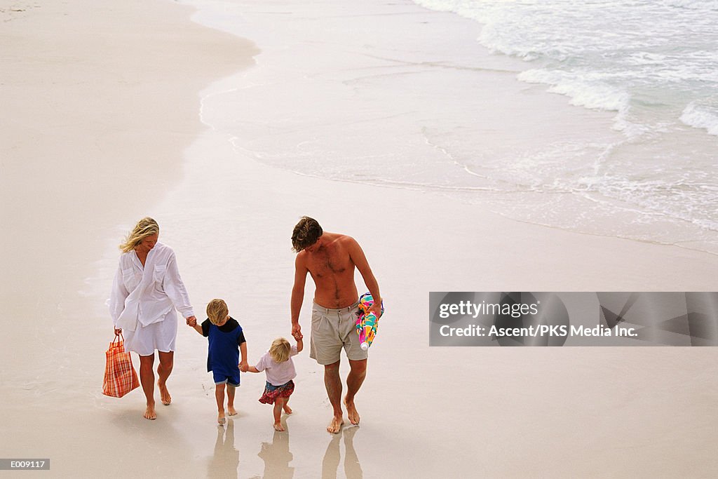 Family holding hands, walking along beach