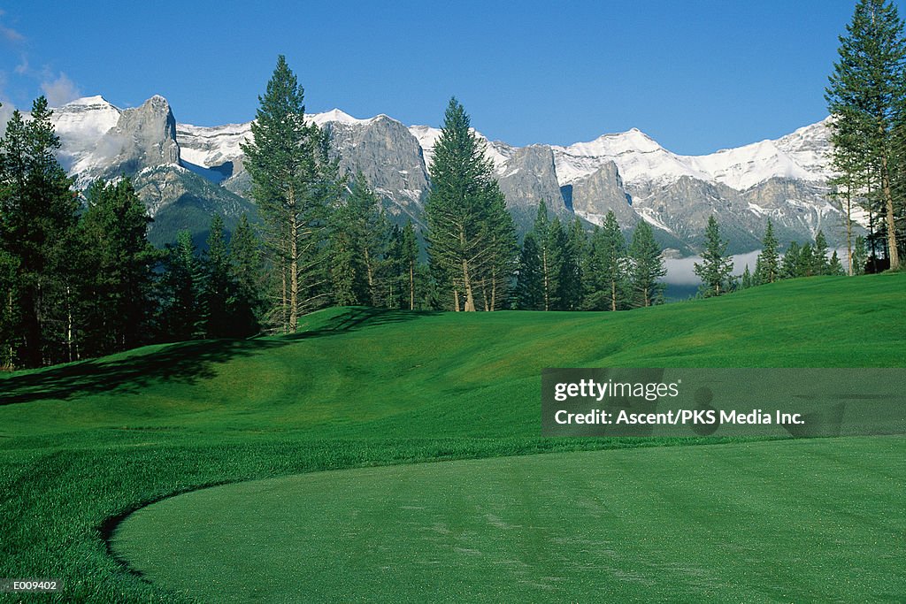 Golf course with trees & mountain peaks