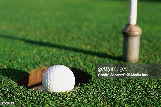 golf ball falling into hole - falling stock-fotos und bilder