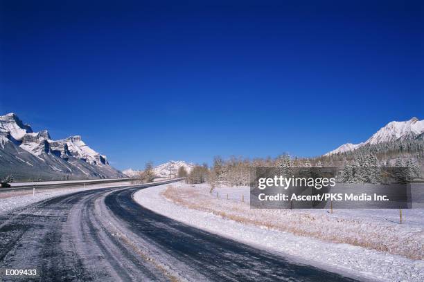 wintry country road with mountains - snösörja bildbanksfoton och bilder