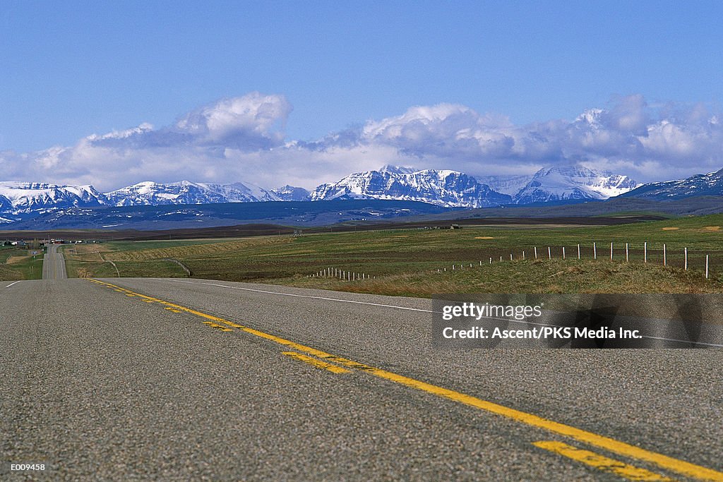 Rural highway with snowy mountains in background